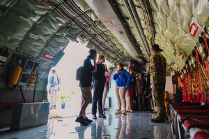 Students listen to a military member inside an aircraft.