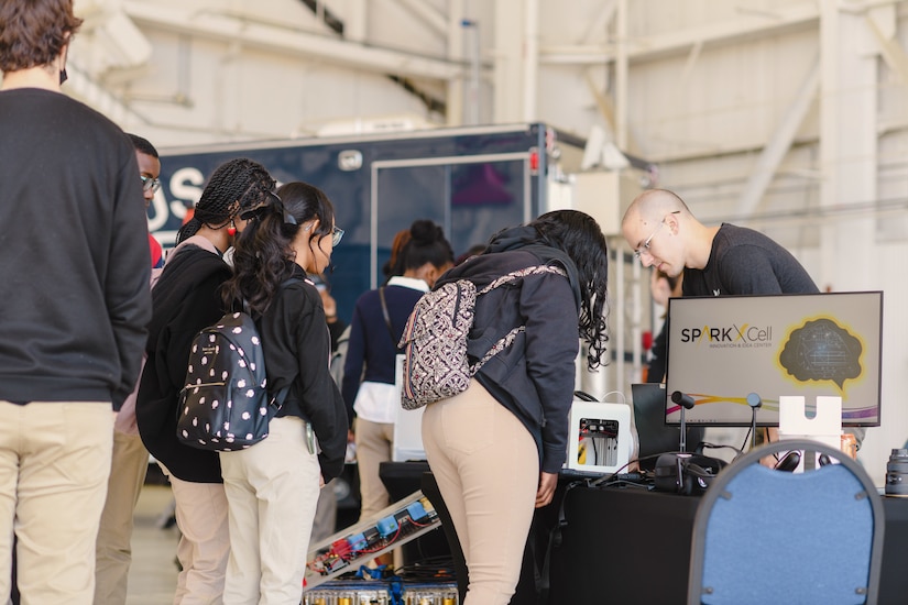 Students stand at an exhibit table.