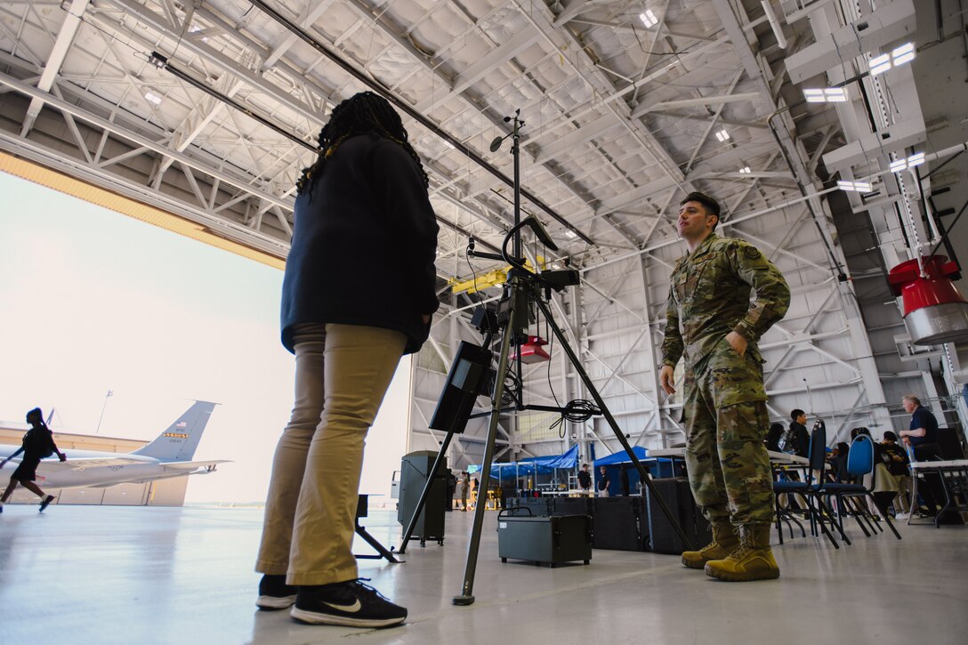 A military member speaks with a student at an exhibition.