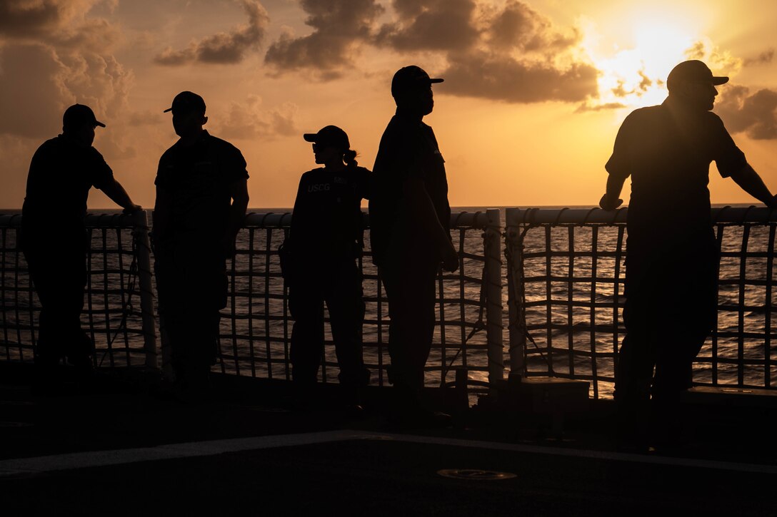 Crew members assigned to USCGC Stone (WMSL 758) watch the sunset while underway in the Atlantic Ocean, Jan. 23, 2023. Stone is on a scheduled multi-mission deployment in the South Atlantic Ocean to counter illicit maritime activities and strengthen relationships for maritime sovereignty throughout the region. (U.S. Marine Corps photo by Corporal Ethan Craw)
