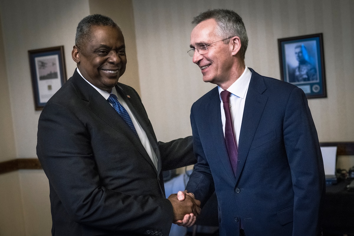 Two men smile and shake hands.