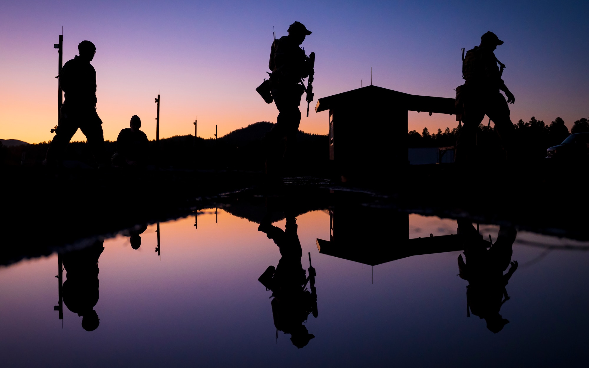 U.S. Air Force members assigned to the 56th Civil Engineer Squadron Explosive Ordnance Disposal flight cross over a swale filled with water on a firing range at Camp Navajo, Arizona, April 10, 2023.