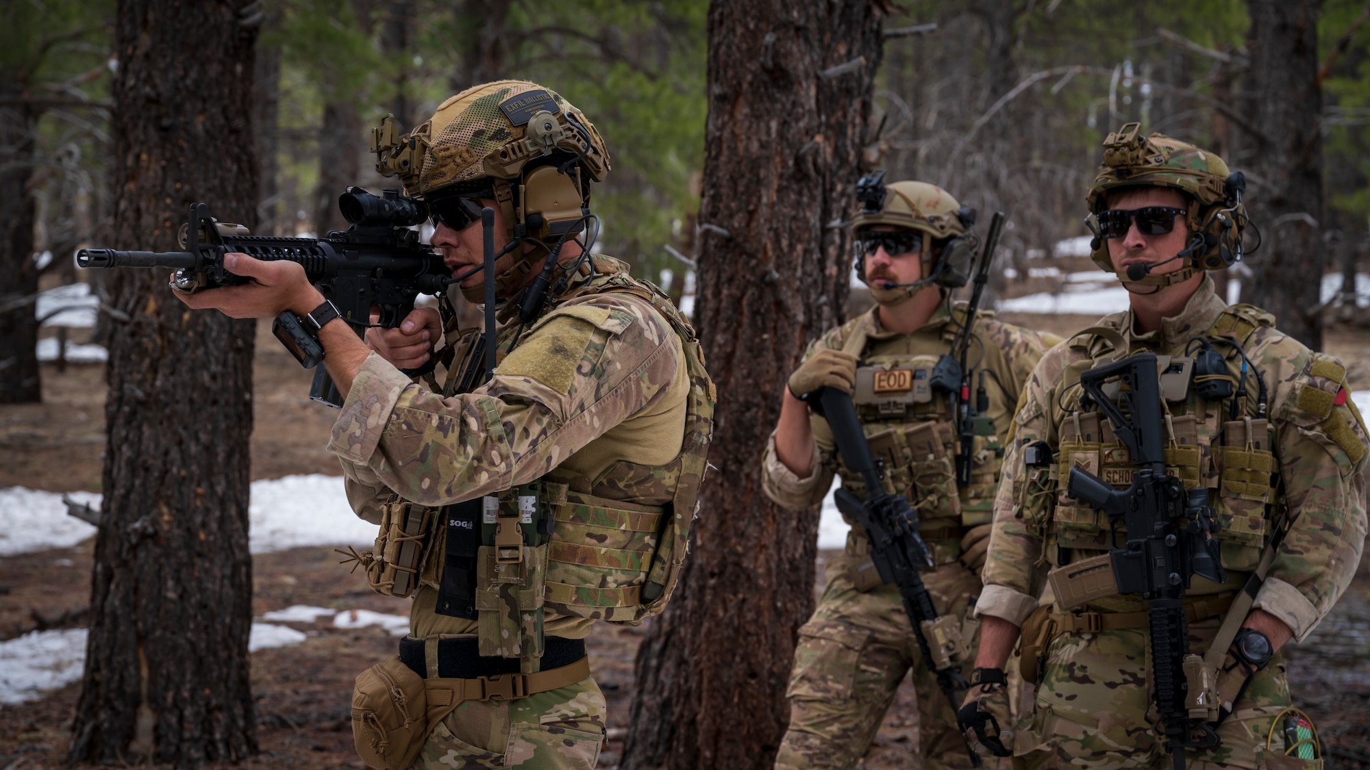 U.S. Air Force Tech. Sgt. Tyler Paul (left), Senior Airman Seth Elroy (center), and Senior Airman Jacob Schoonmaker (right), 56th Civil Engineer Squadron Explosive Ordnance Disposal flight technicians, investigate an area outside a mock village during a training scenario at Camp Navajo, Arizona, April 12, 2023.