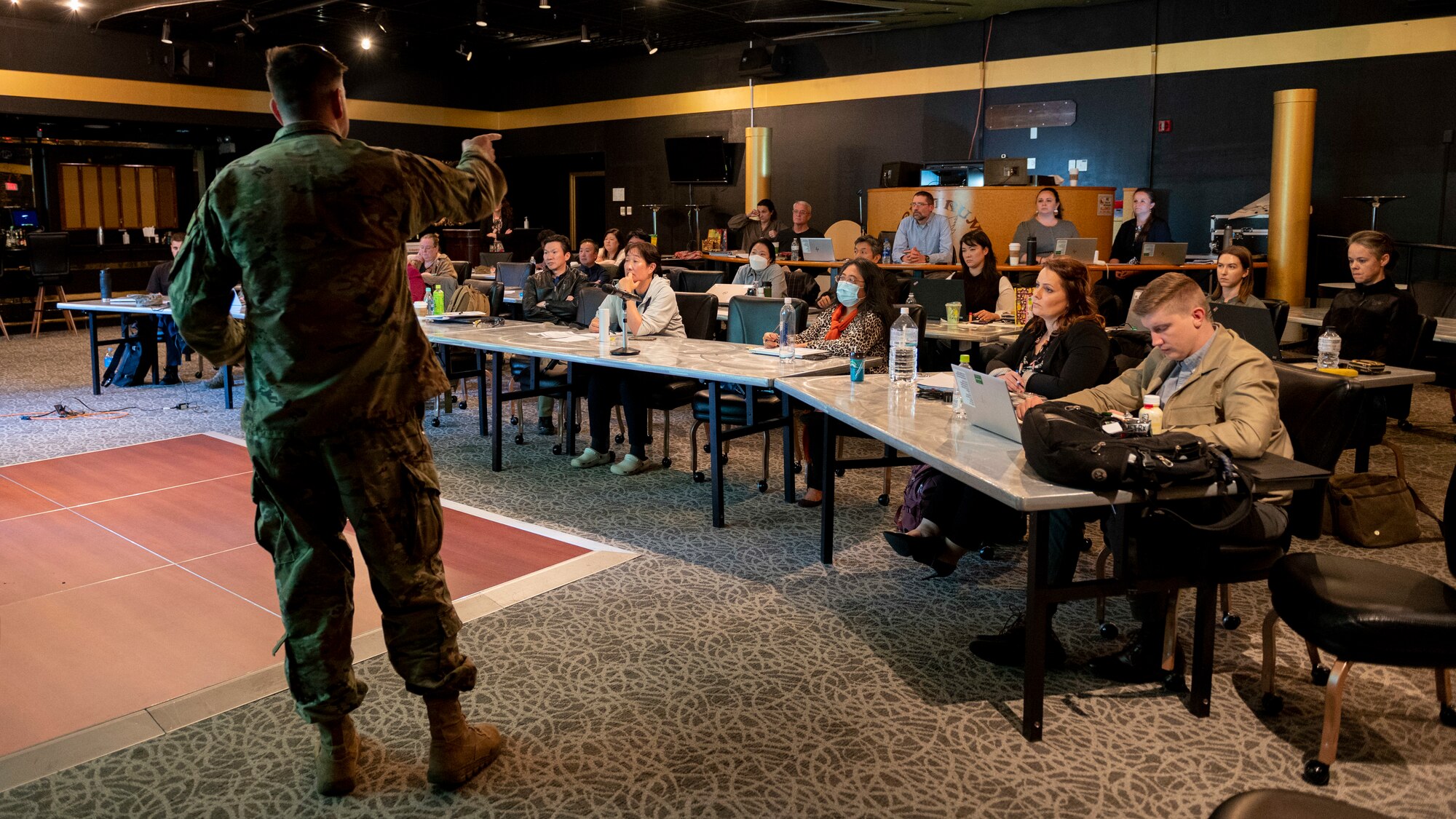 A man in a military unform stands in front of a seated crowd