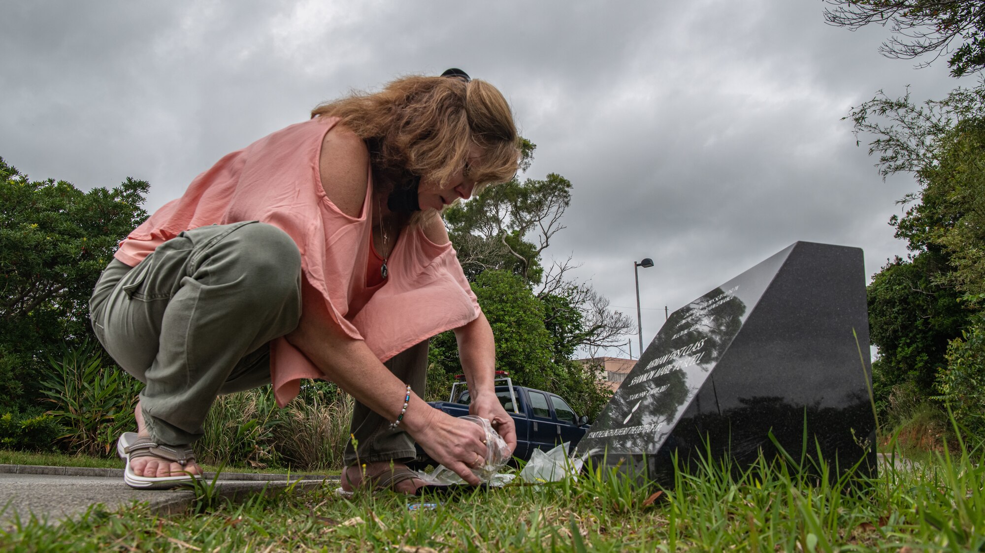A woman places items down at the base of a memorial.