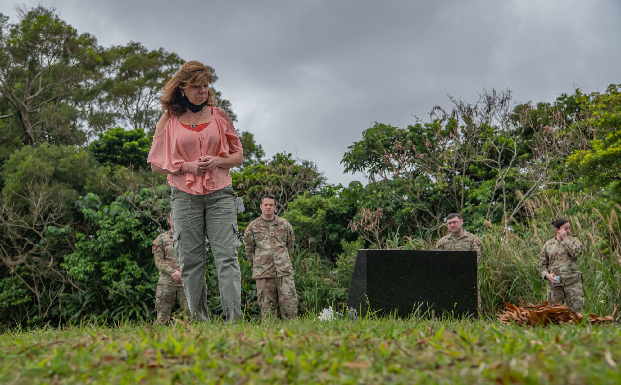 A woman stands somberly at the foot of a memorial.