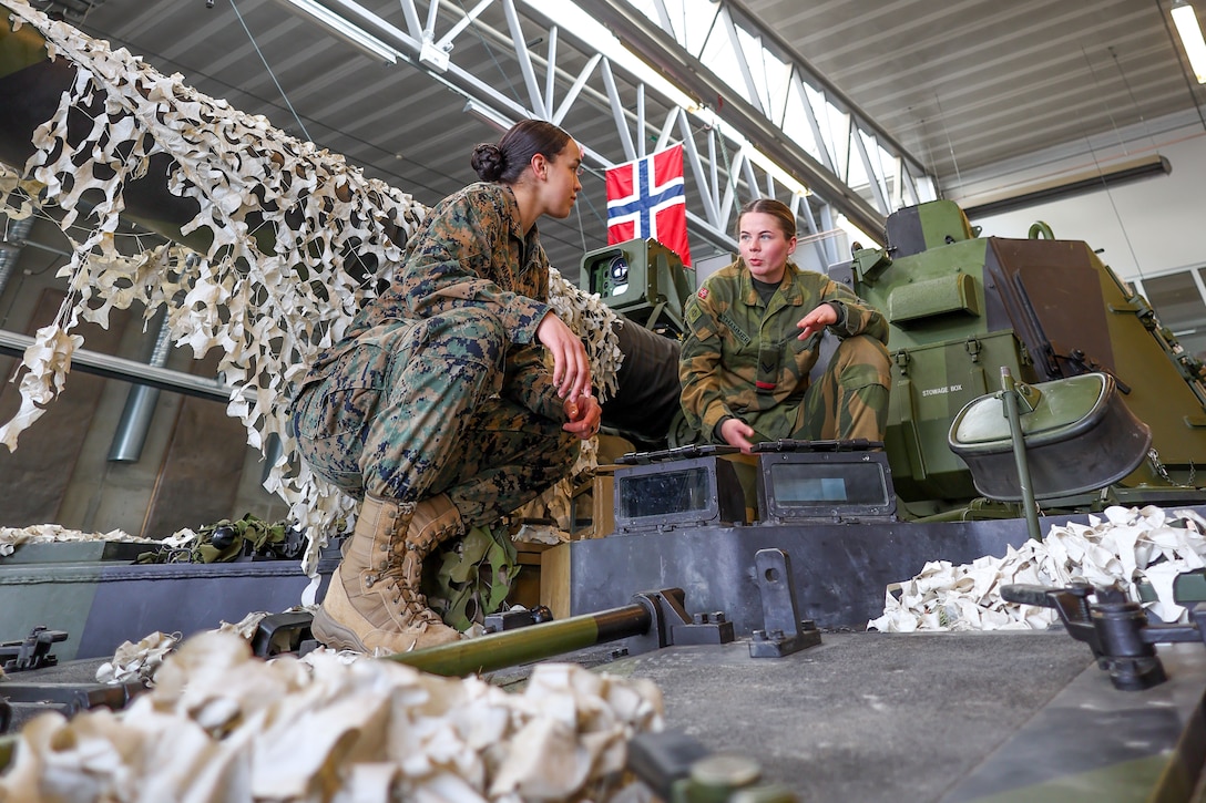 Norwegian soldier Cpl. Ingeborg Athammer with Artillery Battalion Battery NILS, speaks to U.S. Marine Corps 1st Lt. Coral Warren, Air Defense Control Officer, from Springfield, MO, about the K9 VIDAR self-propelled howitzer during the FIRES Summit hosted by Norwegian Armed Forces in Setermoen, Norway, April 19, 2023.