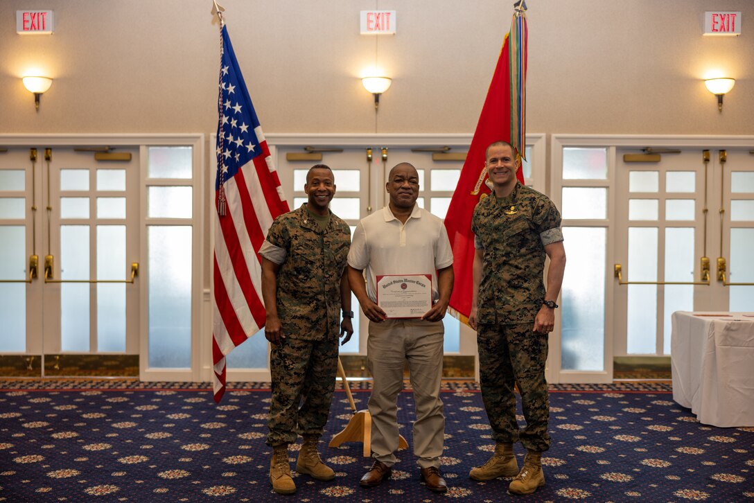 Malcolm Kennedy, a civil service employee, center, receives a certificate of commendation from U.S. Marine Corps Col. Michael L. Brooks, base commander, Marine Corps Base Quantico, left, and Sgt. Maj. Collin Barry, sergeant major, MCB Quantico, right, during the Civilian Quarterly Awards at The Clubs at Quantico, Virginia, April 20, 2023. This ceremony recognizes Marine Corps Base Quantico civilian employees for the outstanding work they do each day. (U.S. Marine Corps photo by Lance Cpl. Joaquin Dela Torre)