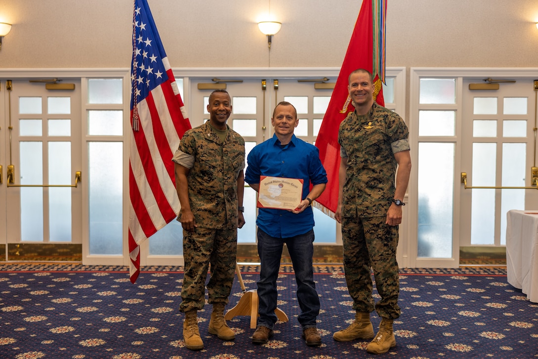 Trever D. Dill, center, receives a certificate of commendation from U.S. Marine Corps Col. Michael L. Brooks, base commander, Marine Corps Base Quantico, left, and Sgt. Maj. Collin Barry, sergeant major, MCB Quantico, right, during the Civilian Quarterly Awards at The Clubs at Quantico, Virginia, April 20, 2023. This ceremony recognizes Marine Corps Base Quantico civilian employees for the outstanding work they do each day. (U.S. Marine Corps photo by Lance Cpl. Joaquin Dela Torre)