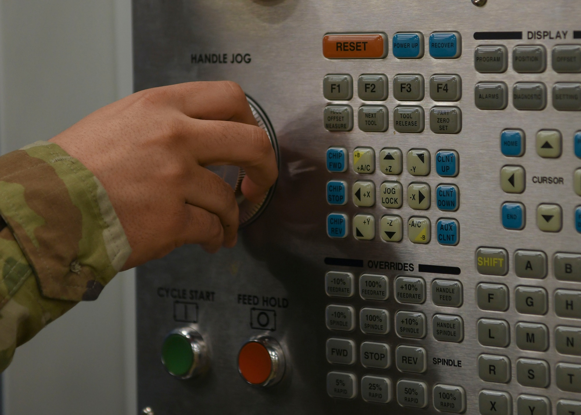 A hand turns a dial on a board full of buttons.