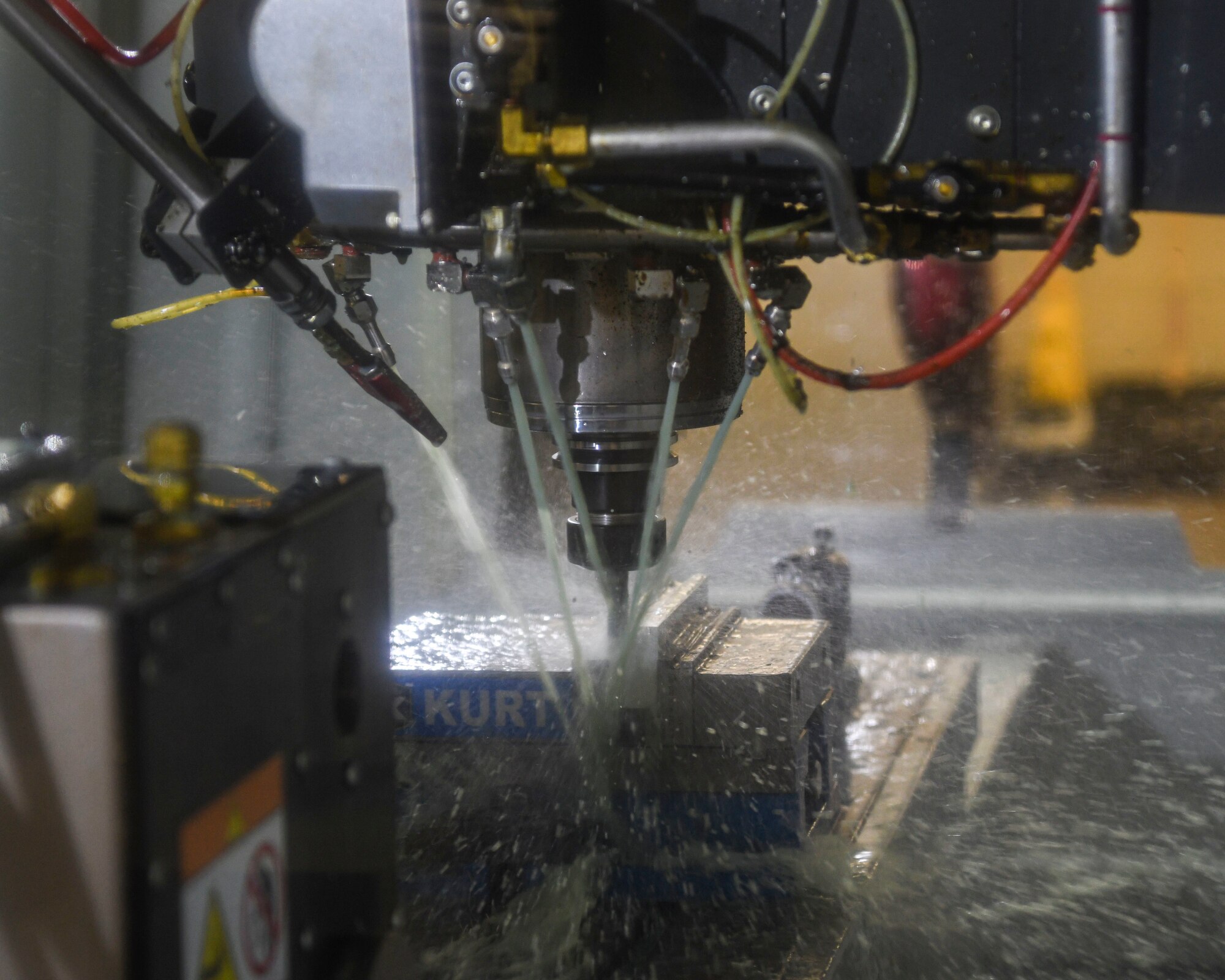 Jets of water spray an automated metal mill as it drills holes into a piece of metal.