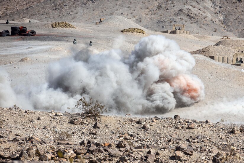 A training explosion is shown in a desert area.