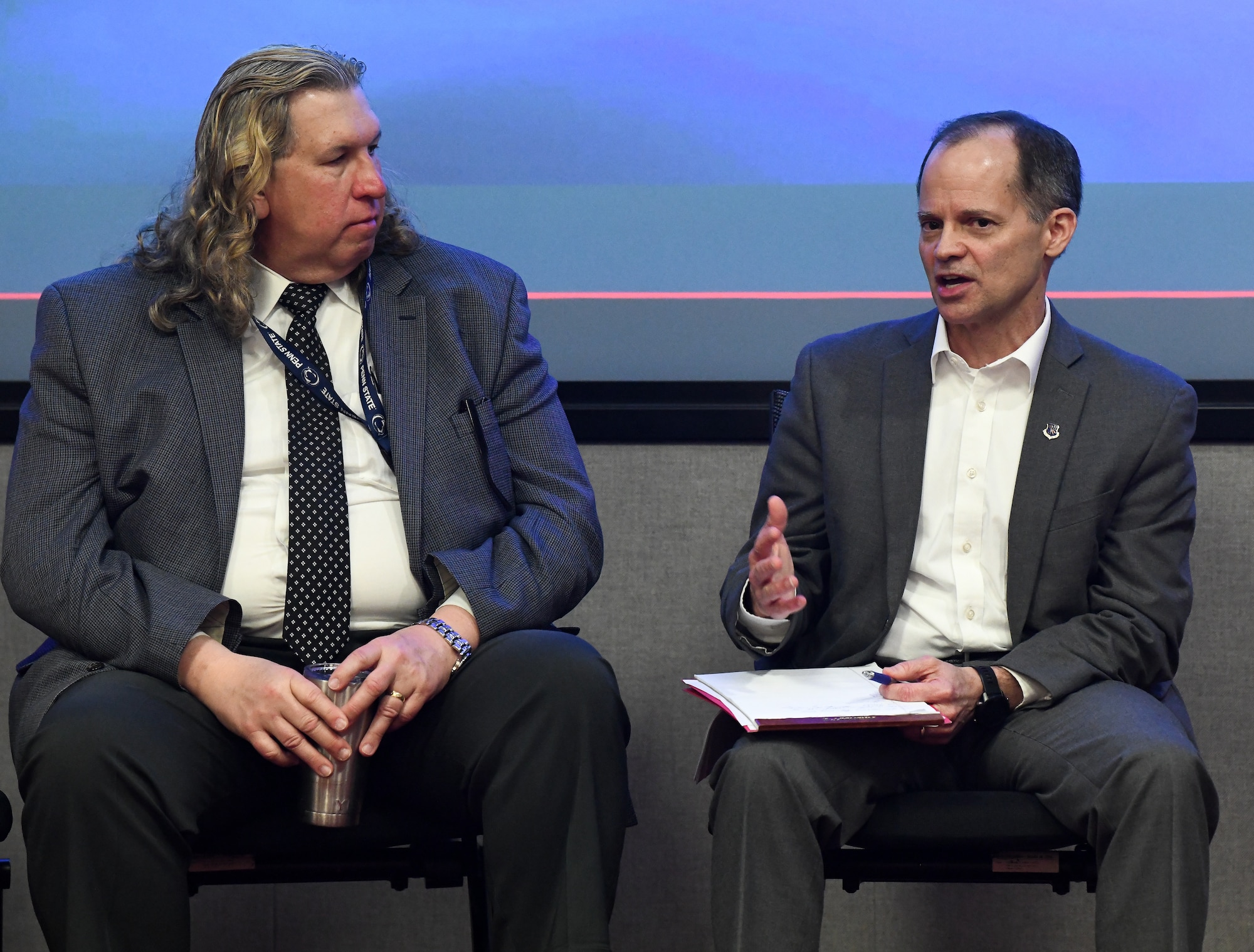 Two men seated, one talking