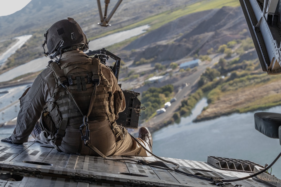 U.S. Marine Corps Sgt. Antonio Trujillo, crew chief, Marine Heavy Helicopter Squadron 461, Marine Aircraft Group 29, 2nd Marine Aircraft Wing, sits on the back of a CH-53K King Stallion while flying over Senators Wash, California, during a training exercise, April 13, 2023. The purpose of this training was to give junior pilots opportunities to fly in a new environment and build cohesion with their crew.