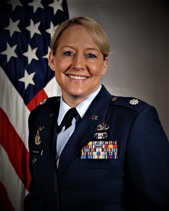 service member smiles for official portrait in front of US flag wearing their service dress.