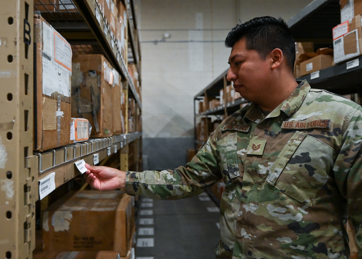 A man in a military uniform looks at a box on a shelf.