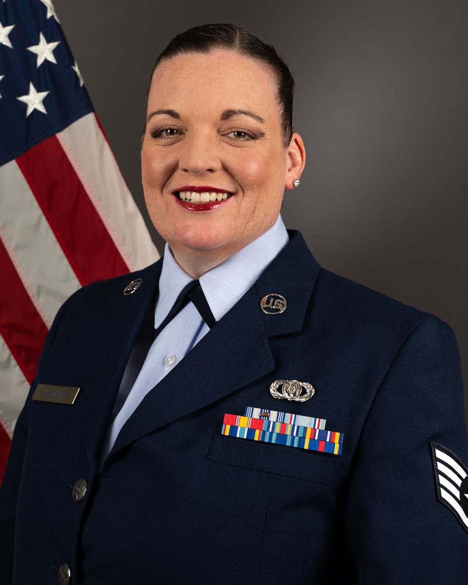 Official photo of Staff Sergeant Julie Keough in front of the American flag. She is wearing the blue service dress uniform