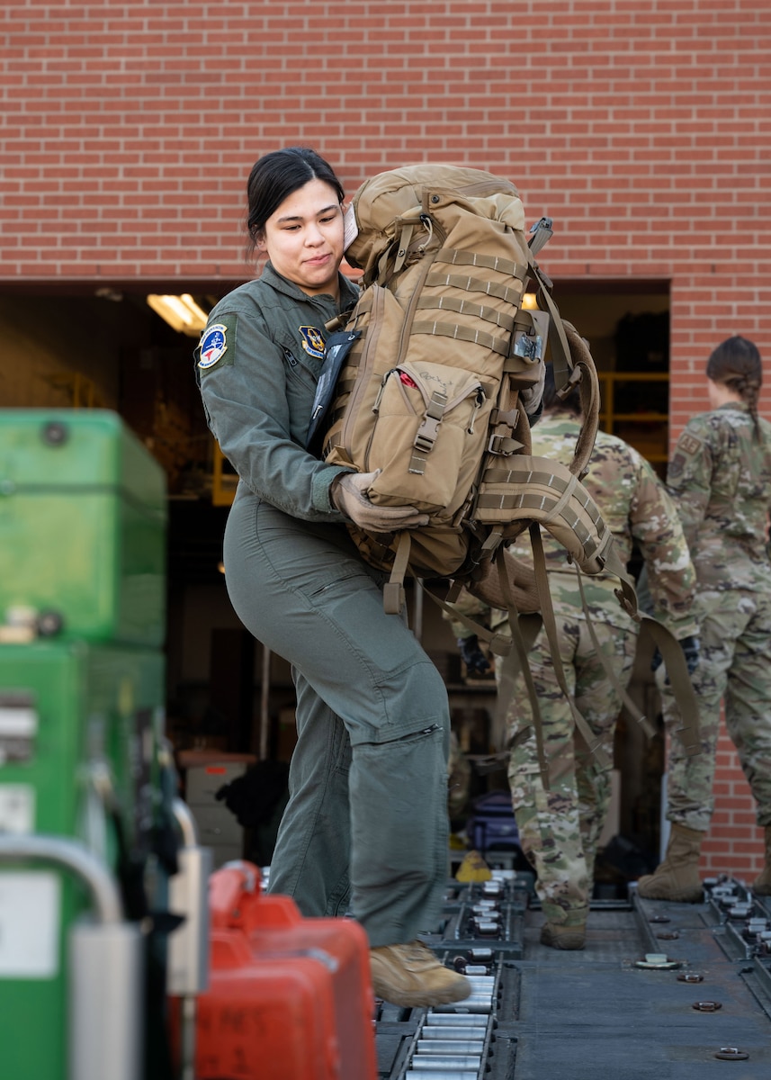 Senior Airman Gretchen Hill, a 934th Aeromedical Evacuation Squadron flight medical technician, lifts a rucksack containing medical supplies onto a cargo loader at the Minneapolis-St. Paul Air Reserve Station, Minnesota, March 23, 2023. Ground and air crew members worked together to load all equipment and luggage by hand. (U.S. Air Force photo by Senior Airman Victoriya Tarakanova)