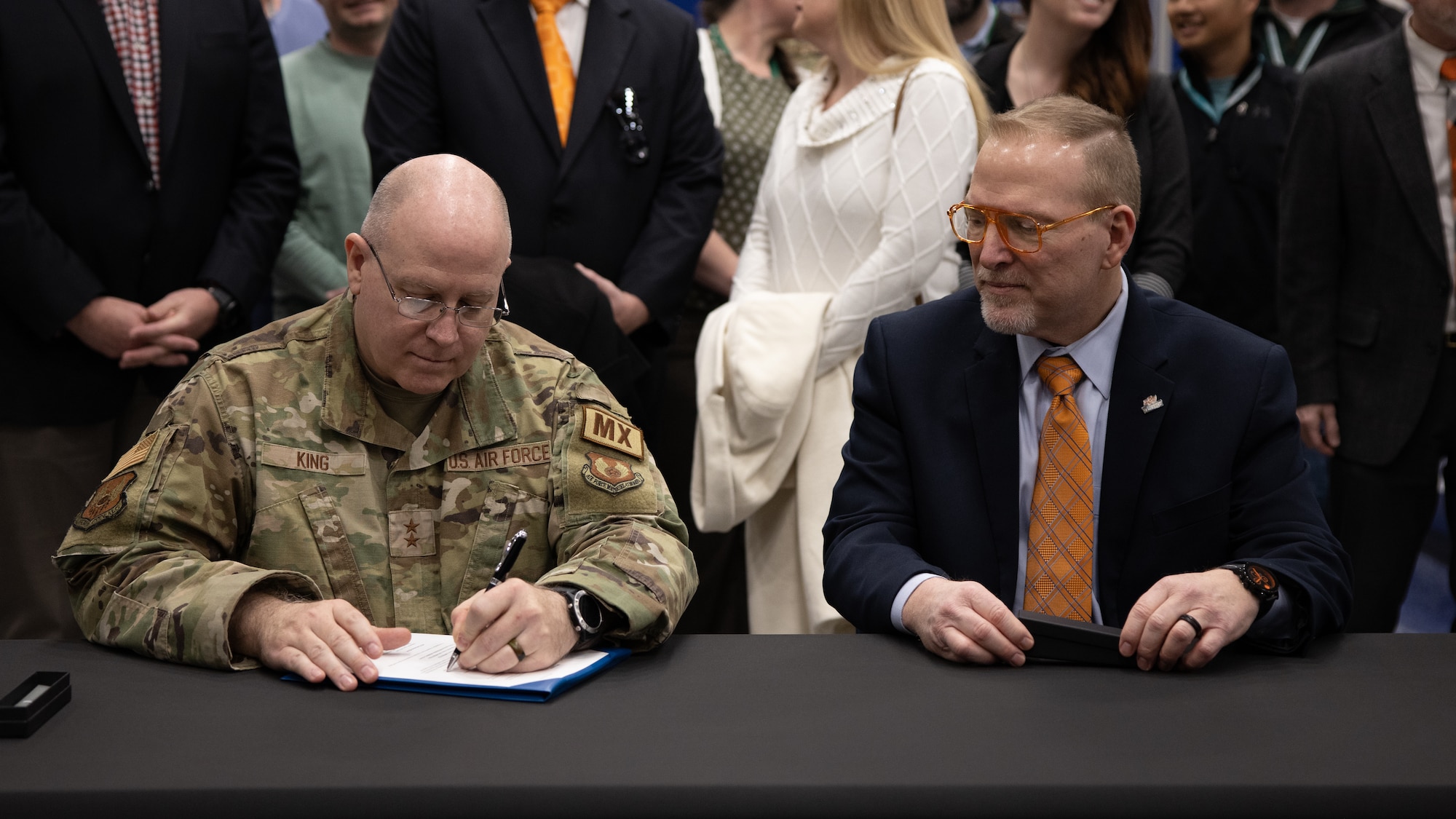 Two men at table signing document