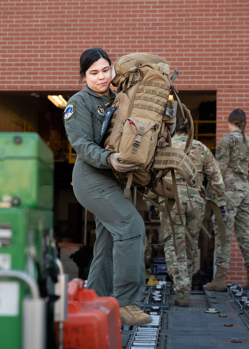 Senior Airman Gretchen Hill, a 934th Aeromedical Evacuation Squadron flight medical technician, lifts a rucksack containing medical supplies onto a cargo loader at the Minneapolis-St. Paul Air Reserve Station, Minnesota, March 23, 2023. Ground and air crew members worked together to load all equipment and luggage by hand. (U.S. Air Force photo by Senior Airman Victoriya Tarakanova)