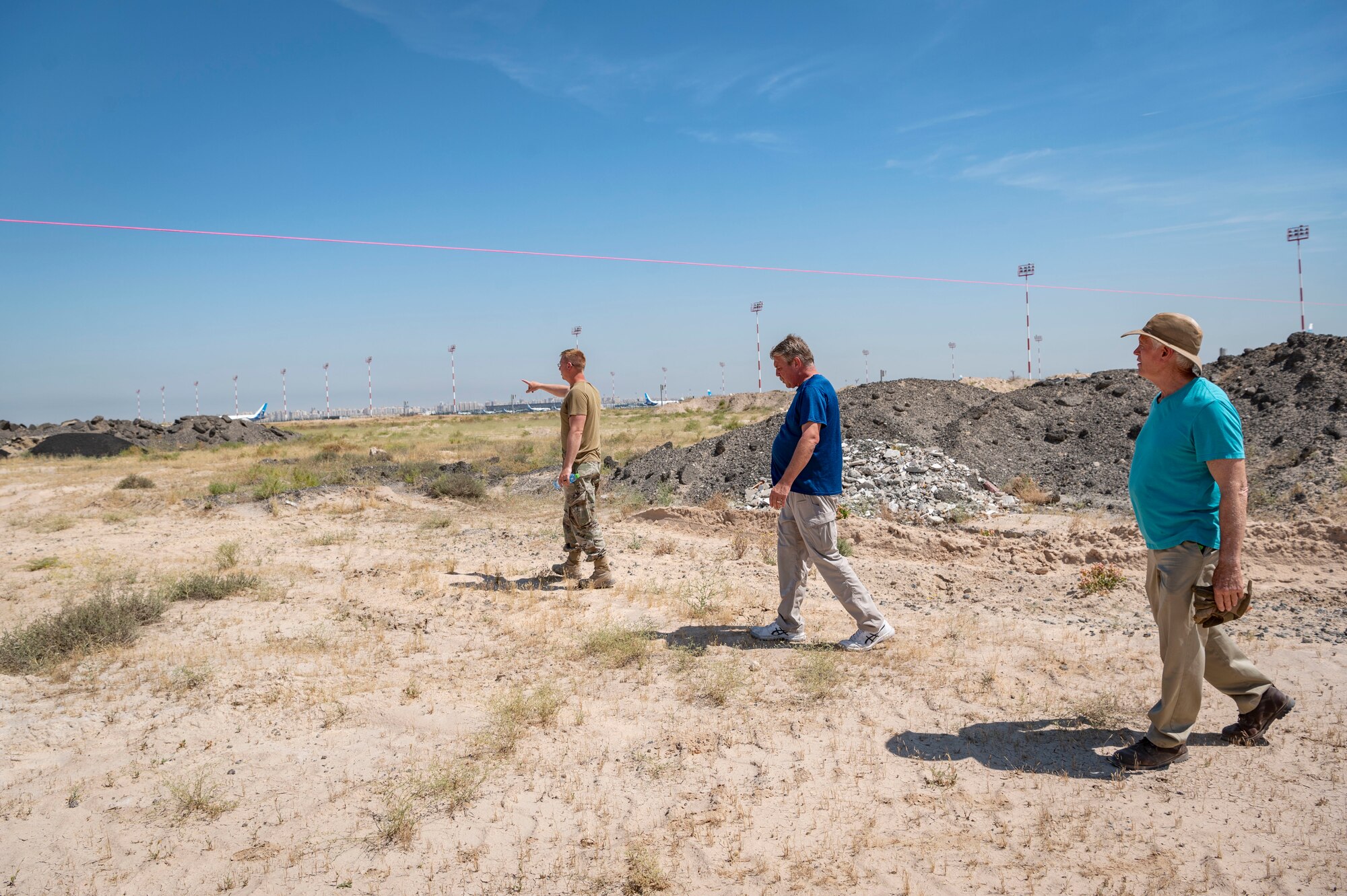 U.S. Air Force Tech. Sgt. Derrick Downey, a 386th Expeditionary Civil Engineer Squadron pavements and construction craftsman, left, and contractors Trey Causey, engineer, center, and Mike May, project planner, right, conduct a site survey during the installation process for a new tower at Cargo City, Kuwait, April 19, 2023.