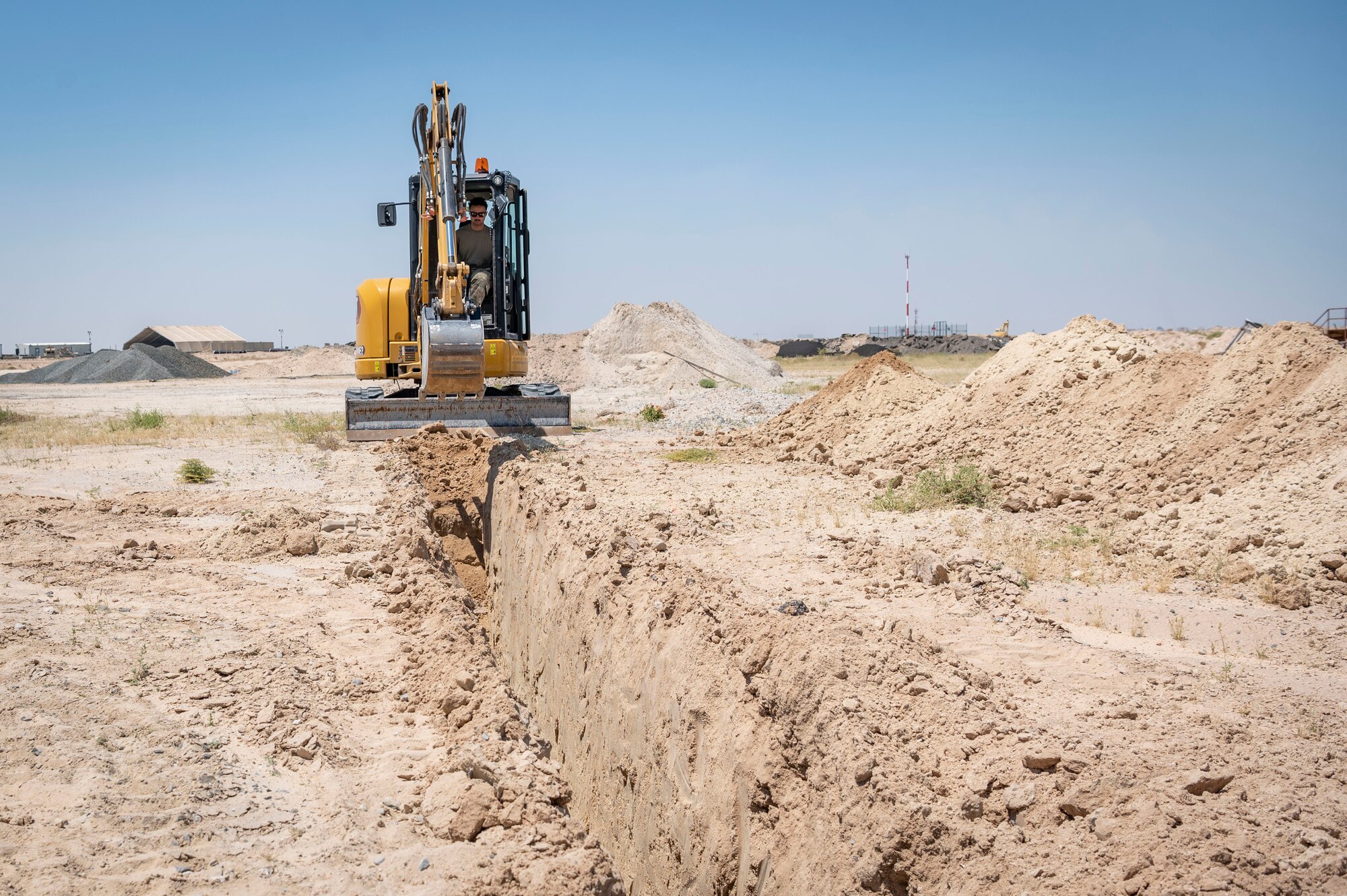 U.S. Air Force Airman 1st Class Ian Mitchell, a 386th Expeditionary Civil Engineer Squadron pavements and construction journeyman, digs a trench during the installation process for a new tower at Cargo City, Kuwait, April 19, 2023.