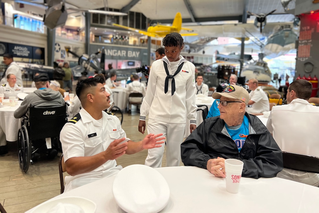 Two sailors speak with a veteran.