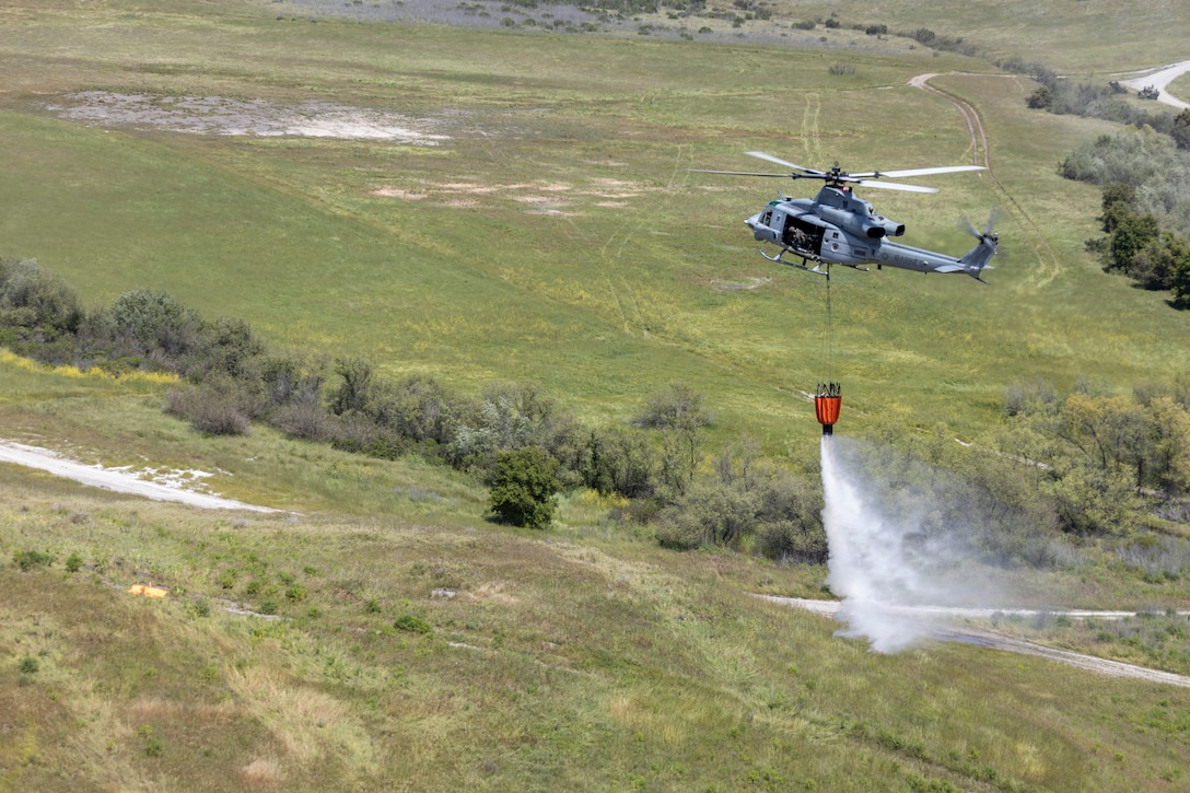 A helicopter drops water from a bucket.