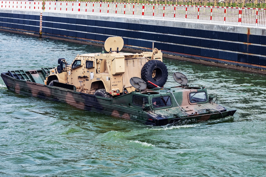 Soldiers operate a medium amphibious transport to ferry a joint light tactical vehicle.