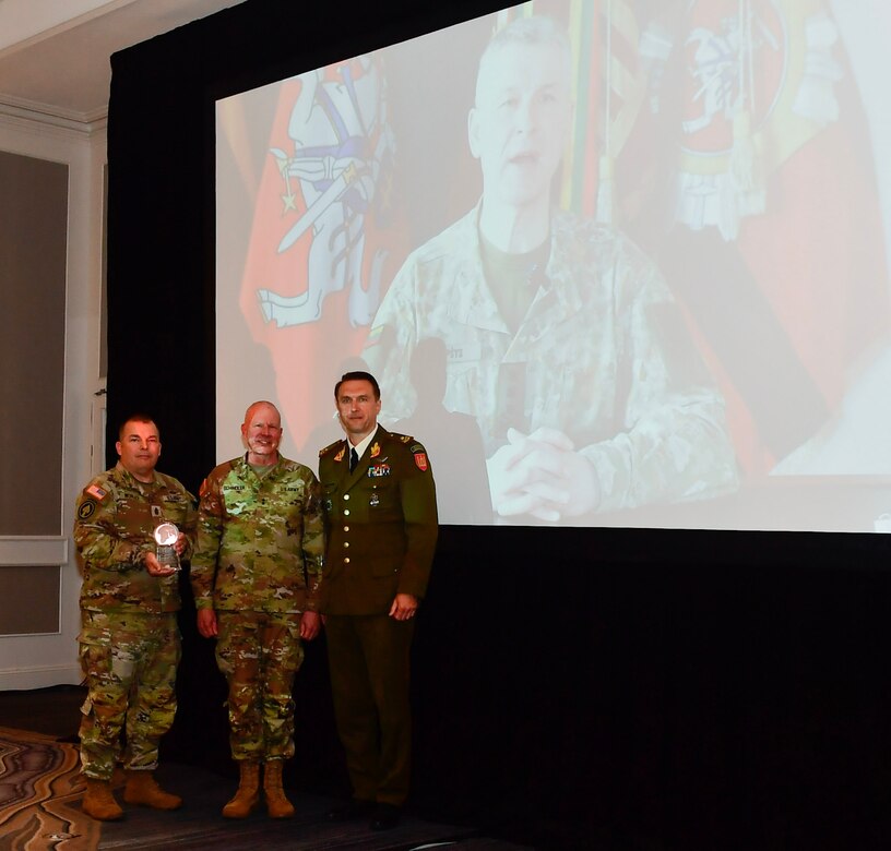 From left to right, Command Sgt. Maj. Jon B. Worley, Senior Enlisted Leader for the Pennsylvania National Guard, Maj. Gen. Mark Schindler, Adjutant General, Pennsylvania National Guard, and Brig. Gen. Modestas Petrauskas, the Defense Attache at the Lithuanian Embassy, pose for a photo after being presented with the 2022 State Partnership of the Year award during an annual State Partnership Program Conference (U.S. National Guard photo by: Sgt. 1st Class Elizabeth Pena)