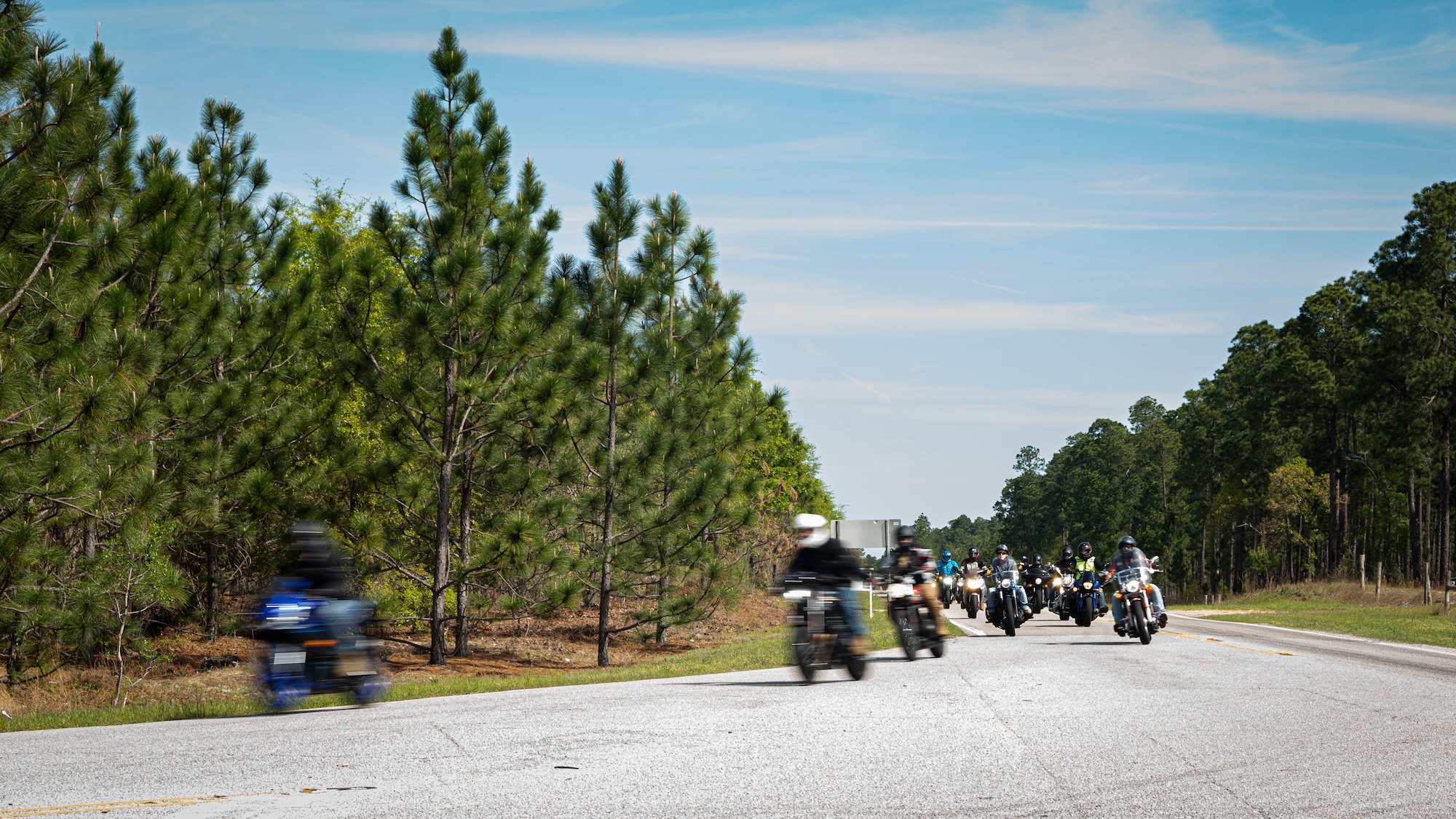 A group of motorcycle riders make a turn in the road.