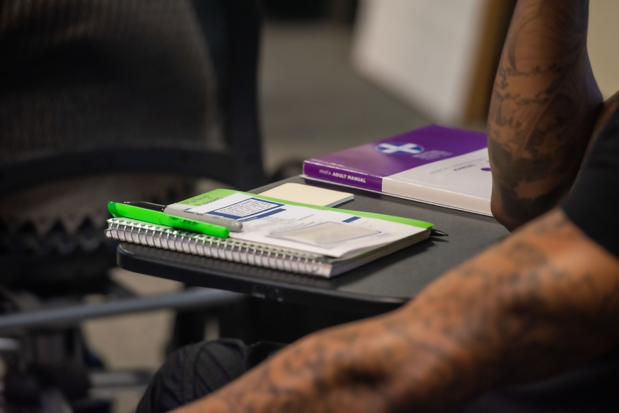 Airman sits on desk with study materials.