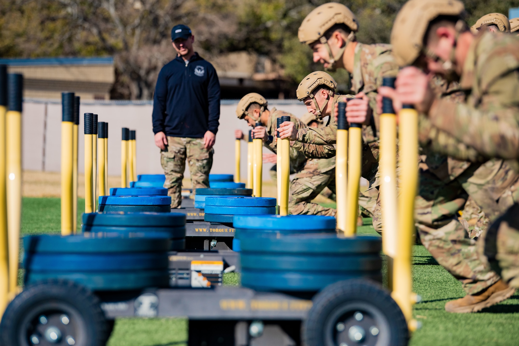 Students prepare to push weighted sleds while coaches monitor training