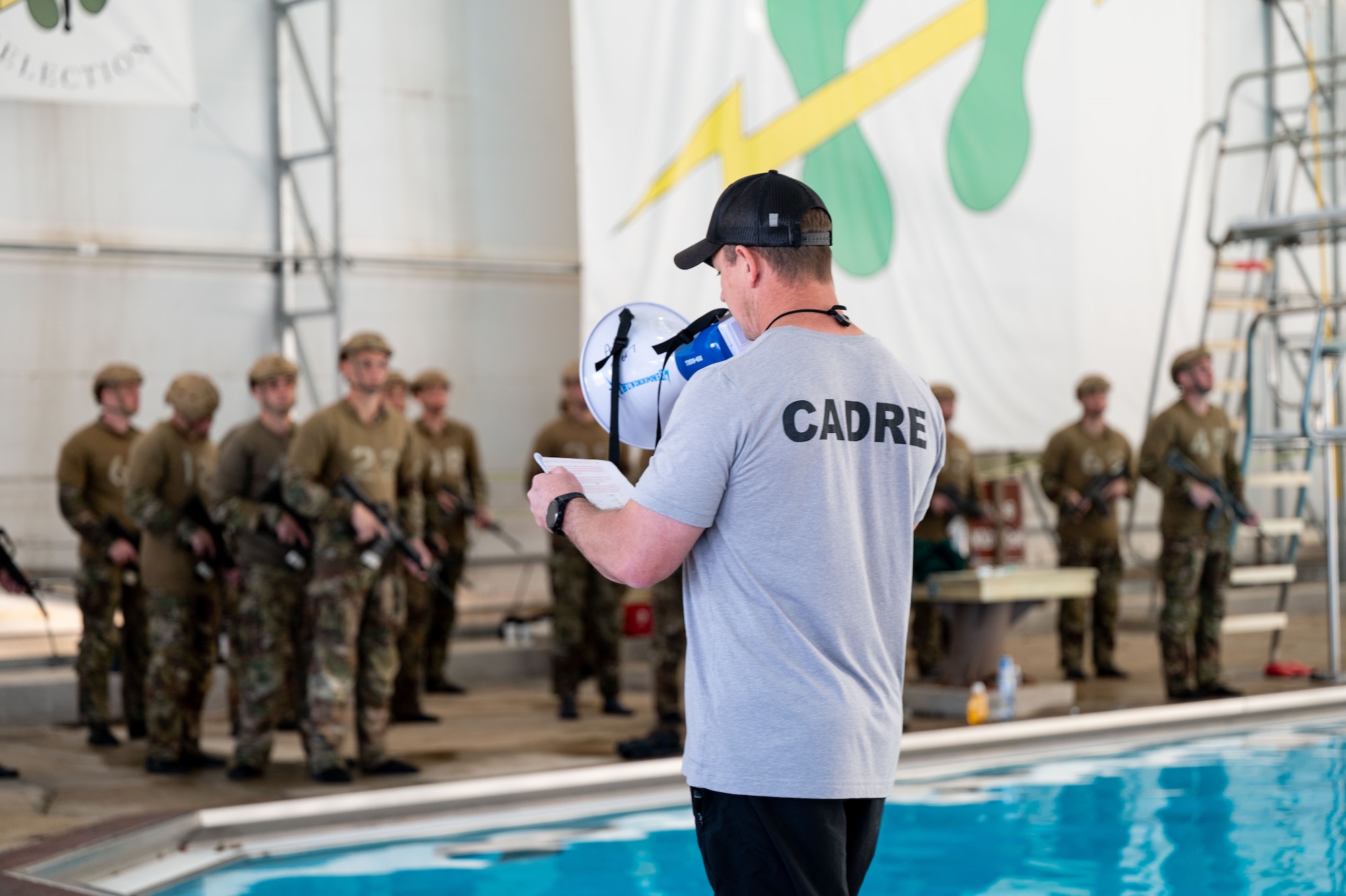 instructor speaks on megaphone to students on edge of pool