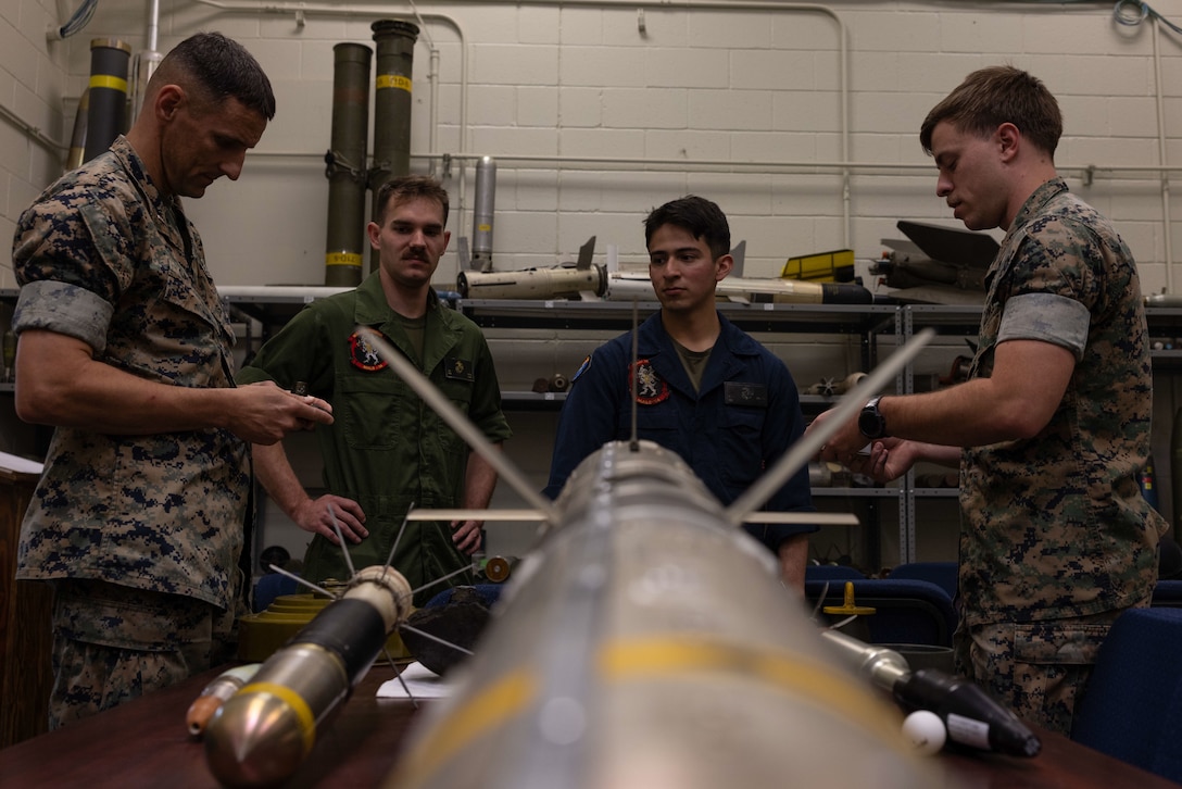 U.S. Marines with Explosive Ordnance Disposal (EOD), far left and far right, inform Marines, center, about the different types of explosives used in the field during an EOD open house event at Marine Corps Air Station (MCAS) Cherry Point, North Carolina, April 12, 2023. This event was hosted to inform Marines about the mission of EOD, provide demonstrations of the equipment utilized to accomplish their mission, and to provide a steppingstone for those interested in transiting into the EOD military occupational specialty. (U.S. Marine Corps Cpl. Jade Farrington)