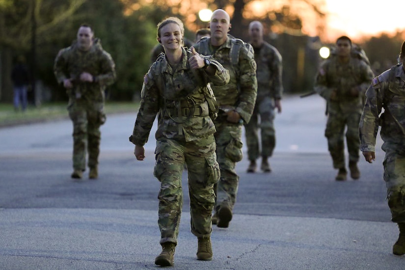 Soldiers walking in the middle of the street with ruck sacks in the early morning.