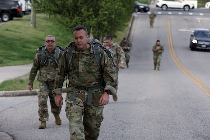 Soldiers walking in the middle of a street in the morning.