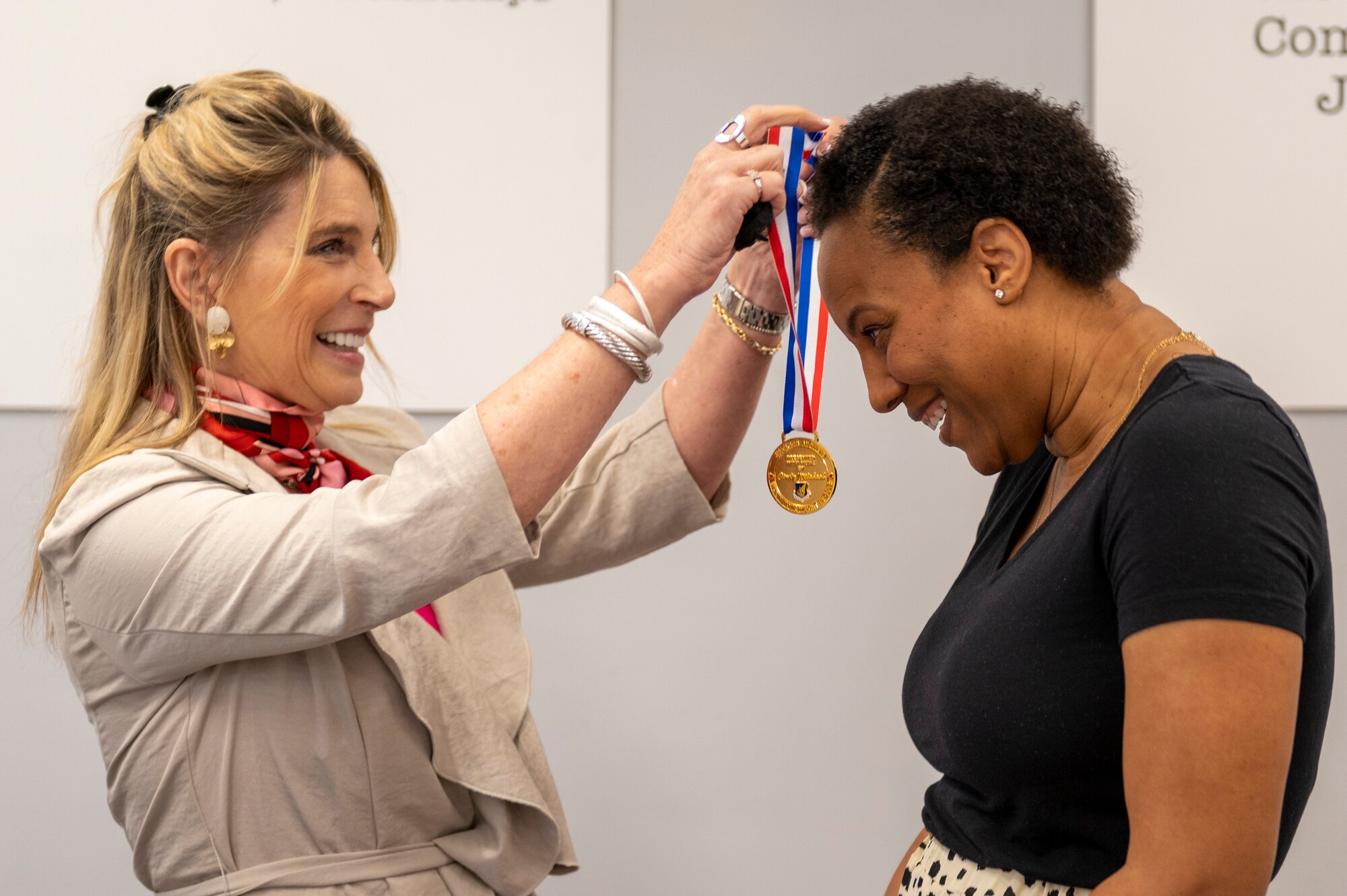 a woman puts a medal onto another woman