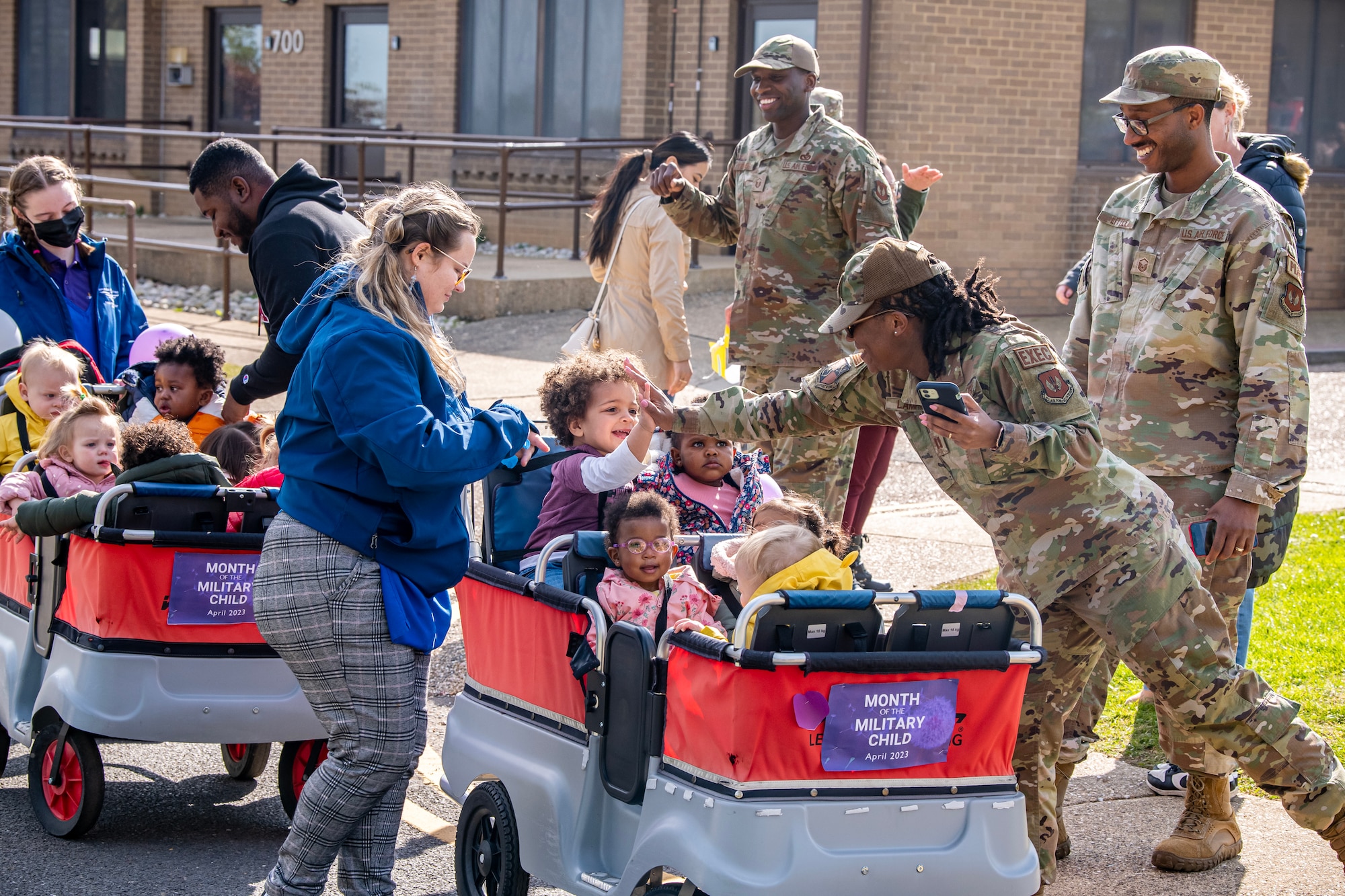 Airmen from the 501st Combat Support Wing cheer on their children during a Month of the Military Child Parade at RAF Alconbury, England, April 25, 2023. The parade was held to show gratitude for the sacrifices that come with being a military child. (U.S. Air Force photo by Staff Sgt. Eugene Oliver)