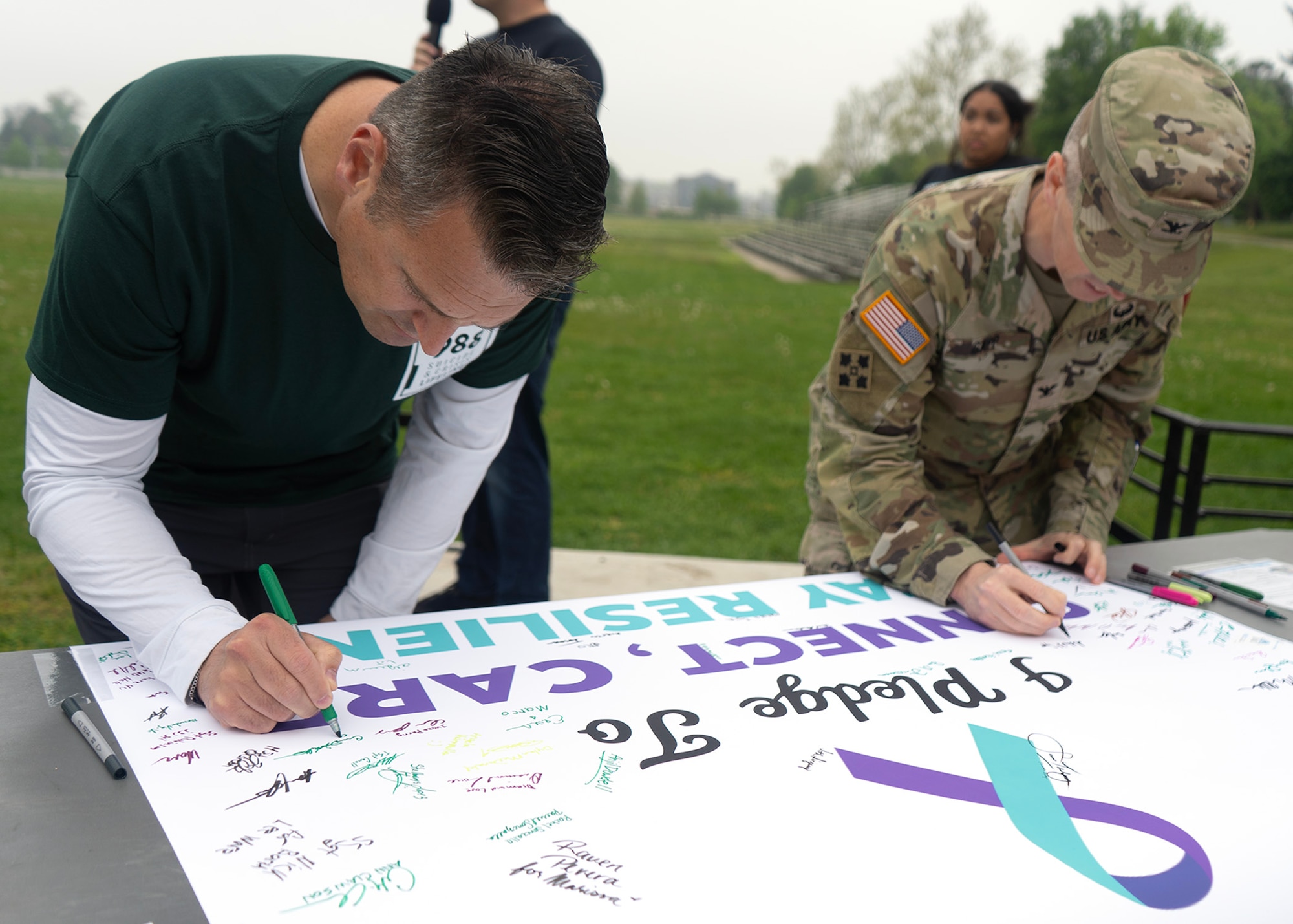 U.S. Air Force Col. Craig Miller, 70th Intelligence, Surveillance and Reconnaissance Wing commander, and U.S. Army Col. Michael Sapp, Fort George G. Meade garrison commander, sign a pledge during a Suicide Awareness Walk, April 21, 2023, at Fort Meade, Maryland. Both commanders pledged support to resiliency, honoring the friends and battle buddies lost, and gaining the tools and resources necessary to support one another. (U.S. Air Force photo by Staff Sgt. Kevin Iinuma)