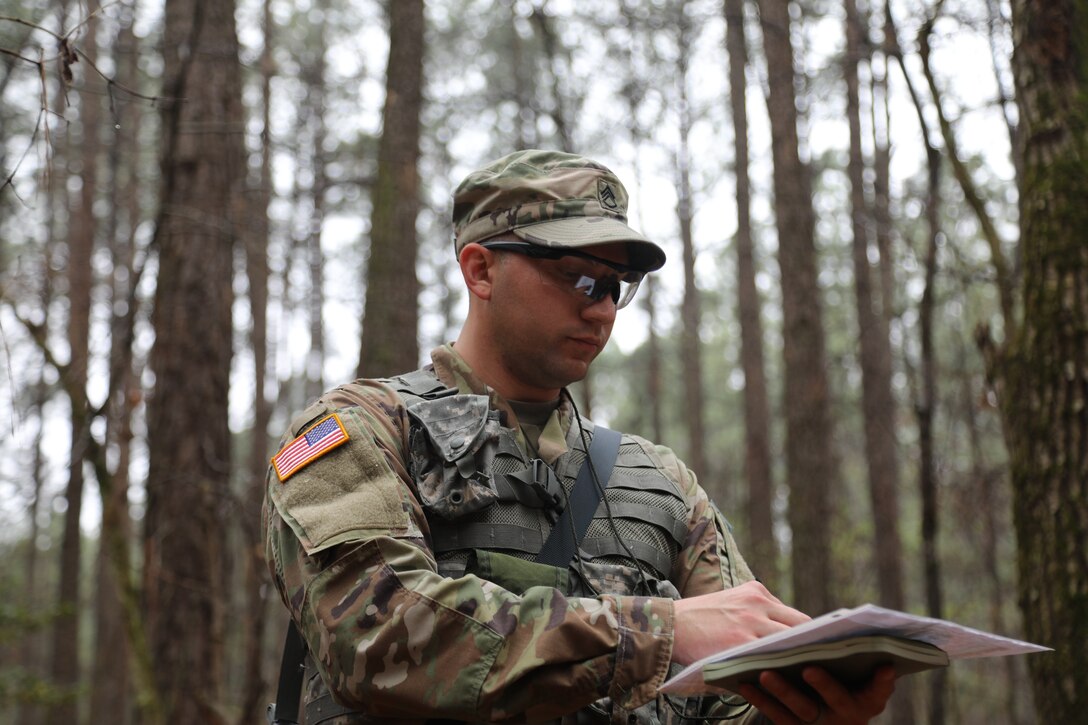 Staff Sgt. Travys Jankowski, a senior IT specialist assigned to the Headquarters and Headquarters Company, 455th Chemical Brigade looks down at his map and compass while he locates his points on the day land navigation course event during the 76th ORC Best Warrior Competition on March 27, 2023 on Fort Lee, Virginia.