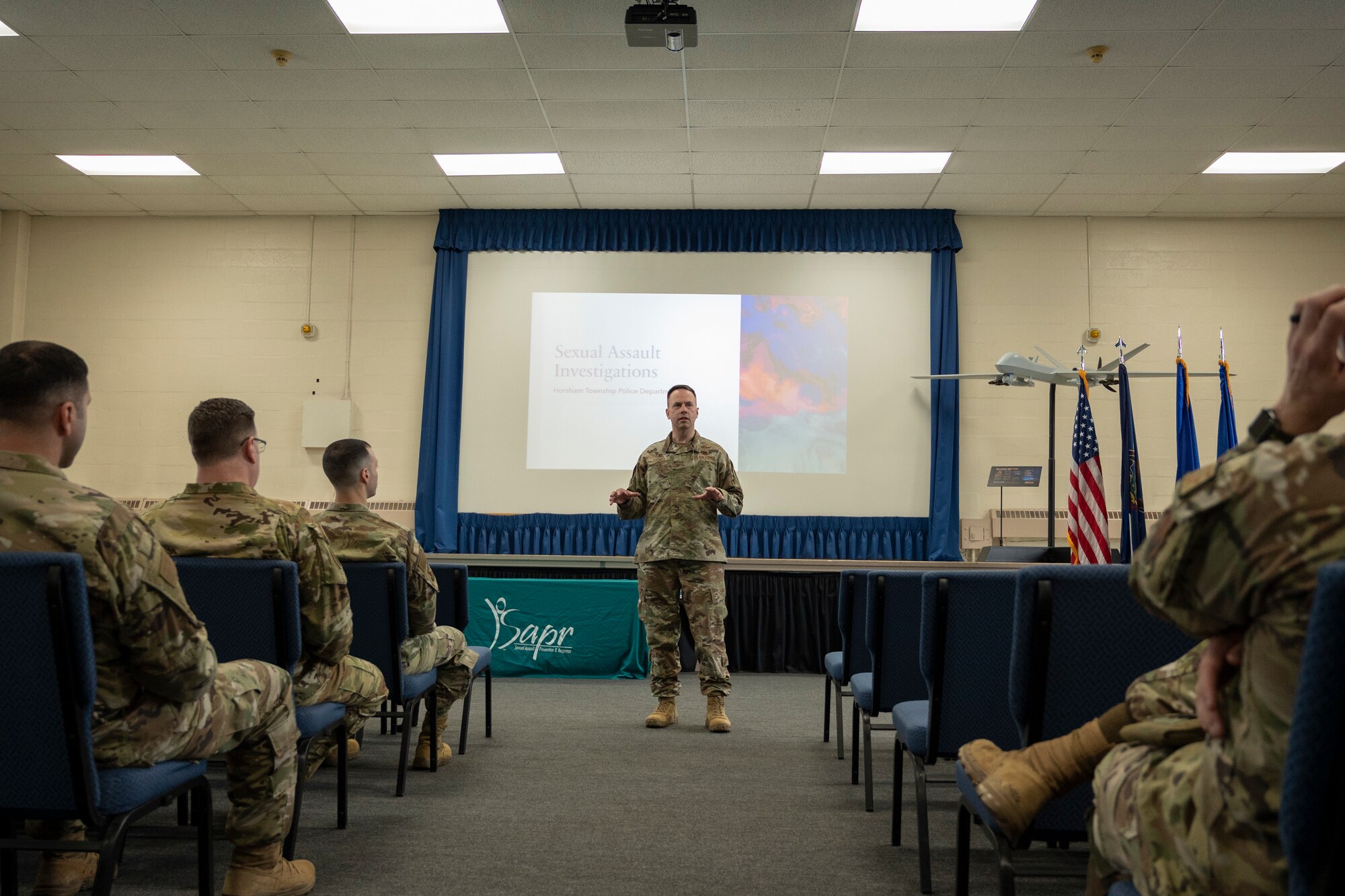 A man in uniform briefs a military audience.