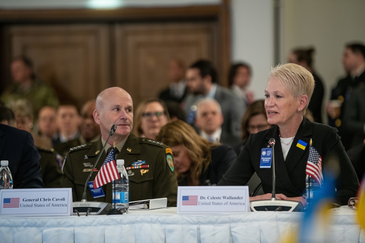 A man in military uniform and a woman sit at a table and speak.