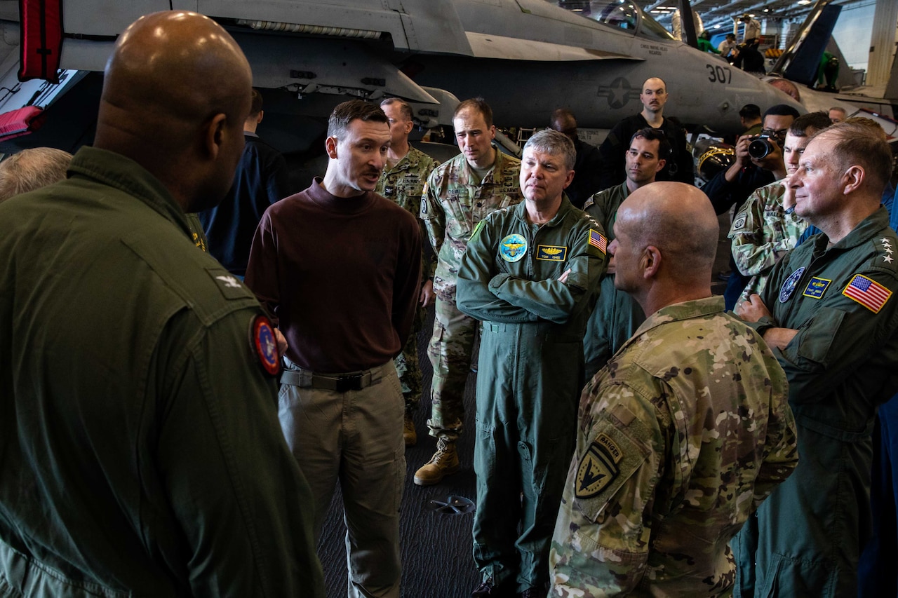 A group of military personnel stand and talk.