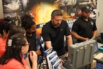 Daniel Swick (center), a robotics technician in NSWC IHD’s Unmanned Systems Branch, describes the interface of an explosive ordnance disposal robot during College of Southern Maryland’s second annual Art of Innovation Science, Technology, Engineering, Arts and Mathematics Festival at the Velocity Center in Indian Head, Maryland, April 22