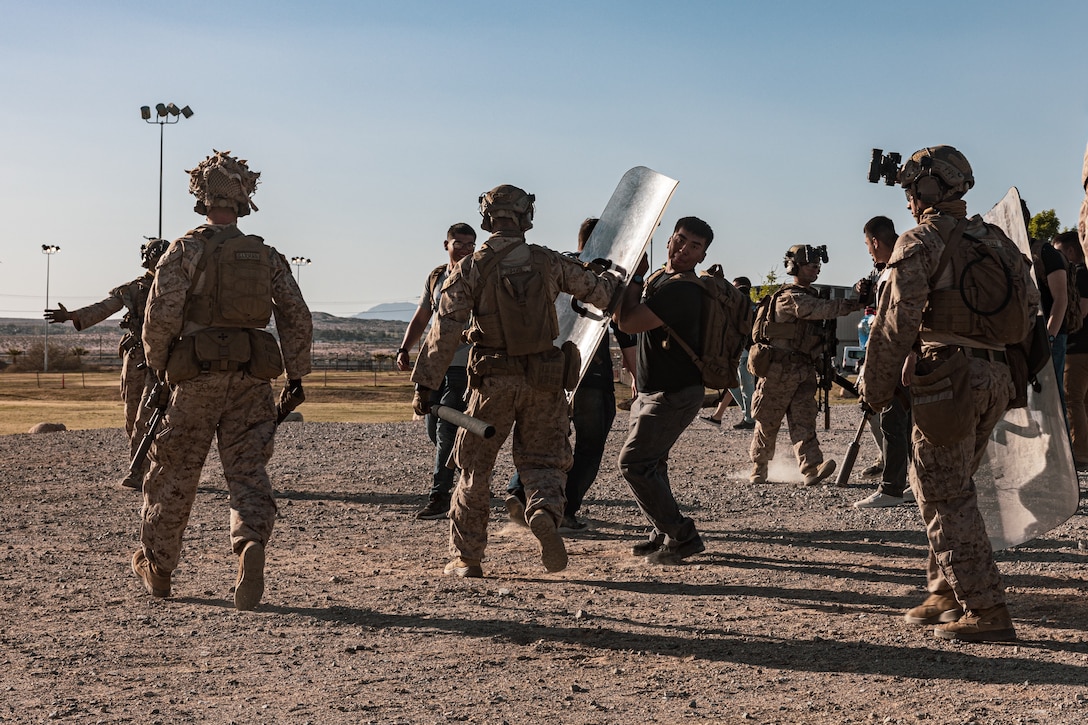 A U.S. Marine with 3rd Battalion, 7th Marine Regiment, 1st Marine Division conducts simulated crowd control during a noncombatant evacuation operation (NEO) exercise