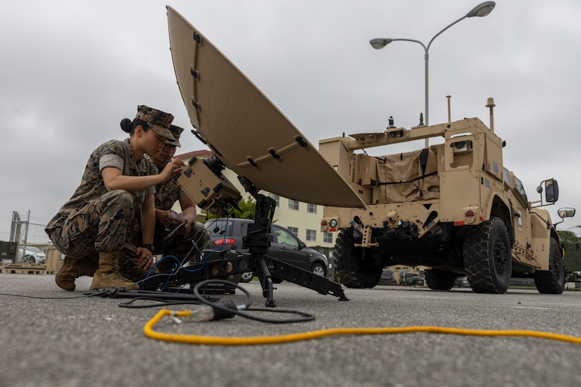 Two Marines work on a satellite dish.