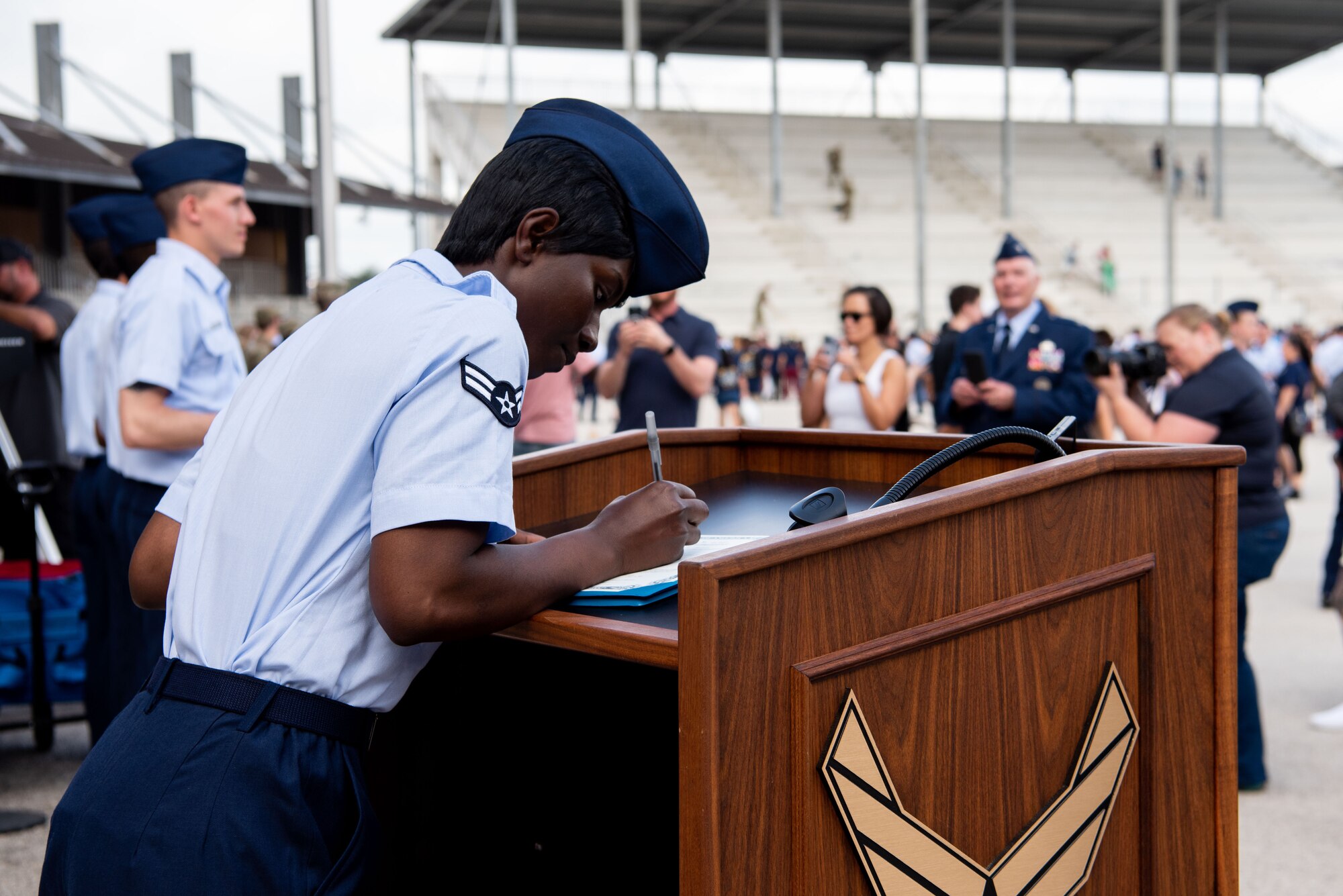 Airman First Class D'elbrah Assamoi from Cote D’Ivoire signs her U.S. Certificate of Citizenship after the Basic Military Training Coin Ceremony at JBSA-Lackland, April 26, 2023. Fourteen Airmen became the first U.S. citizens here under the new streamlined Naturalization Process at BMT. The Airmen were part of approximately 500 trainees from the 326th Training Squadron who graduated this week. The process is part of an effort to revive the naturalization path for immigrants and allow trainees to become citizens before they graduate. It’s just one of several initiatives the Air Force is taking to remove barriers to service amid the current challenging recruiting environment. (U.S. Air Force photo by Vanessa R. Adame)