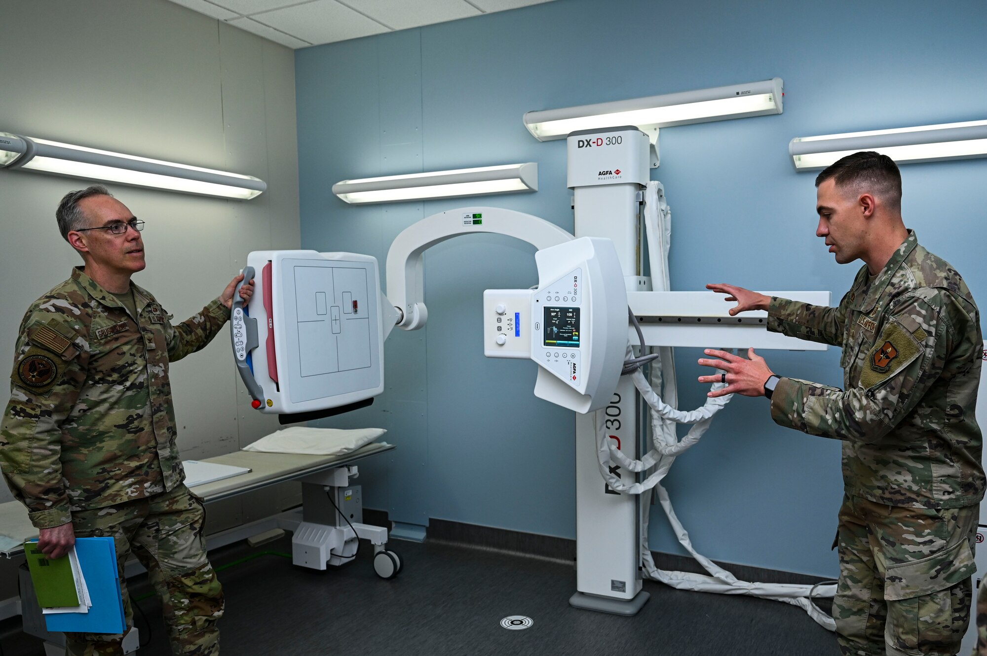 U.S. Air Force Tech. Sgt. Brandon Clement, 49th Medical Group radiology noncommissioned officer in charge, right, explains the capabilities of the DX-D 300 radiology scanner to U.S. Air Force Col. Christopher Grussendorf, Air Education and Training Command surgeon general at Holloman Air Force Base, New Mexico, April 13, 2023. The 49th MDG is responsible for providing care for all Airmen, Guardians, dependents and retirees on base. (U.S. Air Force photo by Airman 1st Class Isaiah Pedrazzini)