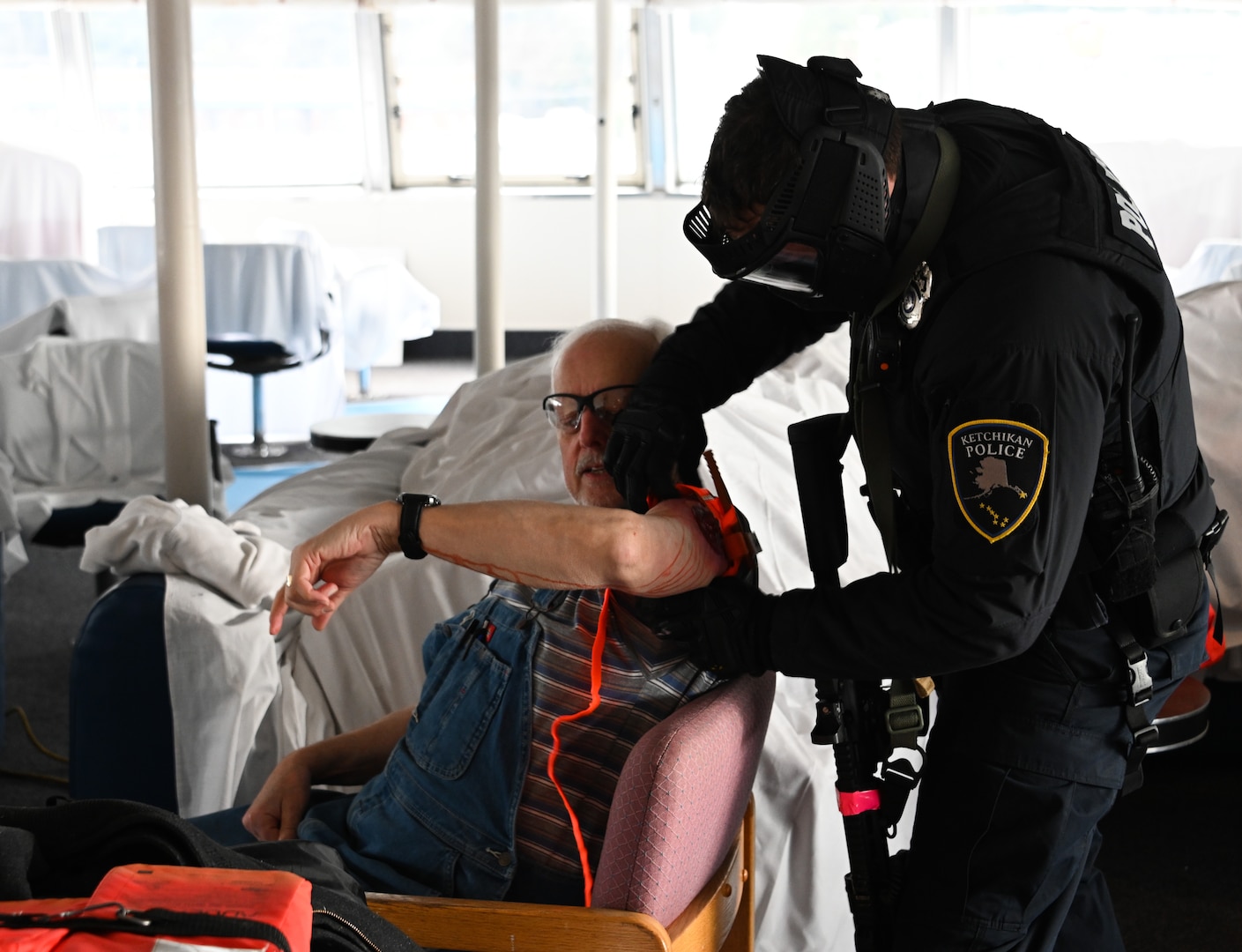 A member from the City of Ketchikan Police Department provides simulated medical treatment to a participant during a full-sale active shooter exercise aboard the Ketchikan Alaska Marine Highway System marine vessel Matanuska in Ketchikan, Alaska, April 26, 2023. The exercise is designed to improve active shooter response protocols and interagency coordination for potential emergencies. U.S. Coast Guard photo by Petty Officer Third Class Ian Gray.